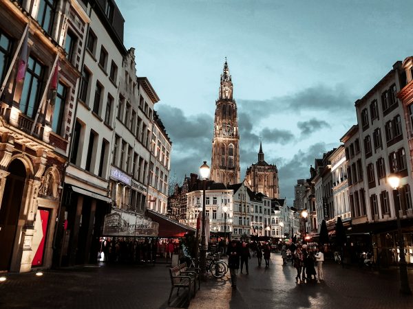 a group of people walking down a street next to tall buildings